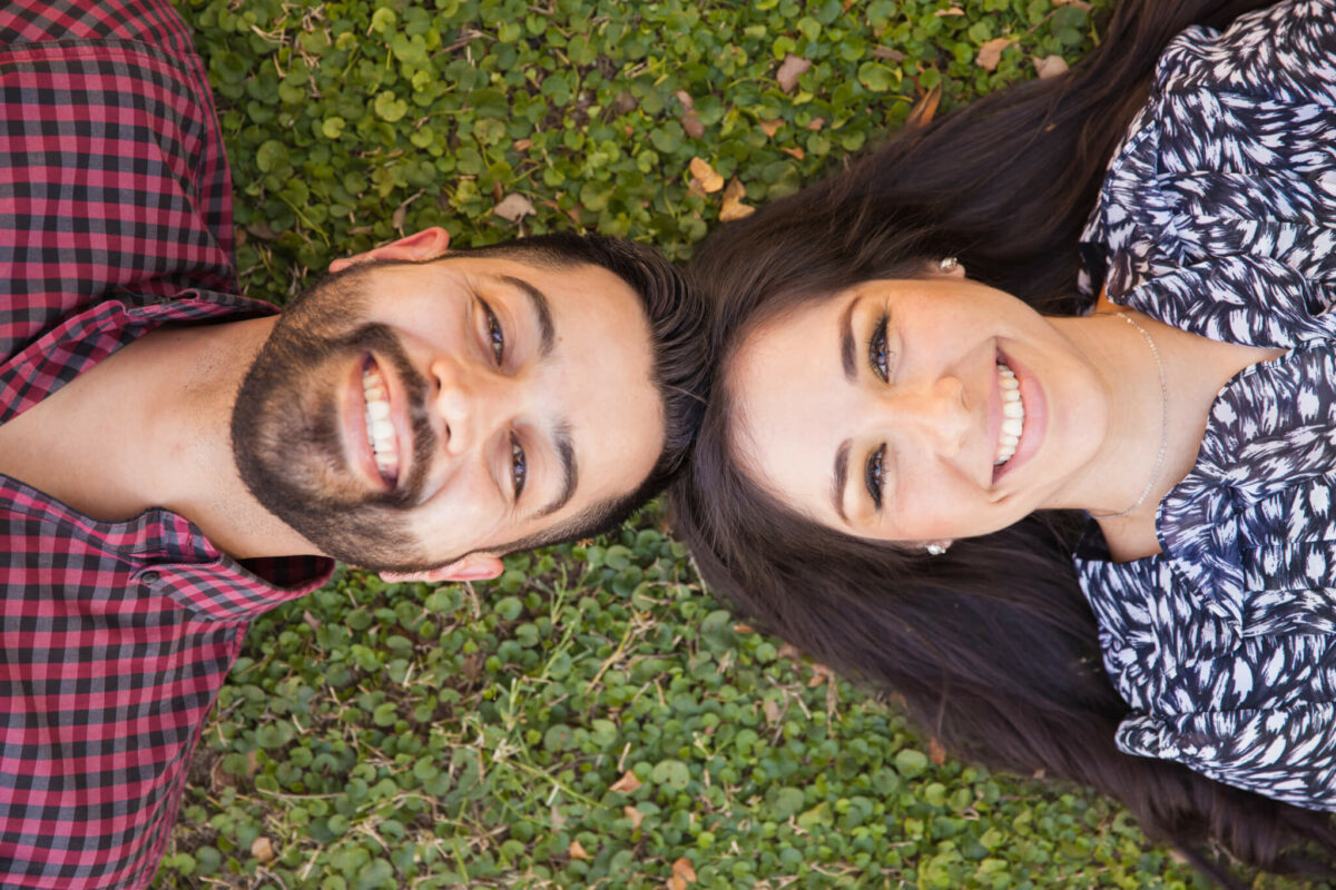 Hispanic couple lying on the grass